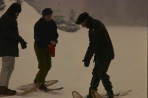 A black and white image of three men on some of the oldest snowboards standing in the snow.